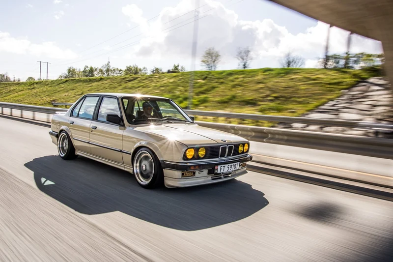 Beige klassisk BMW E30 i fart på motorvei