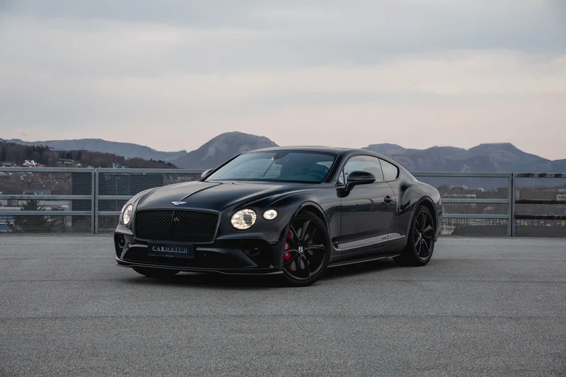 Svart Bentley Continental GT på parkeringsdekk med fjell i bakgrunnen