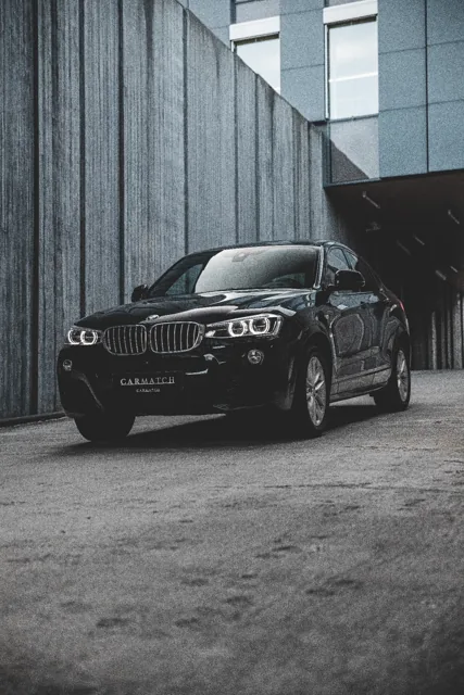 Svart BMW X4 fotografert mot en mørk fasade