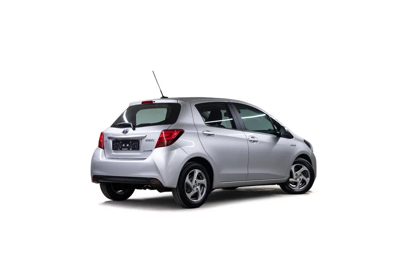 Sølvfarget Toyota Yaris Hybrid fotografert skrått bakfra på hvit bakgrunn