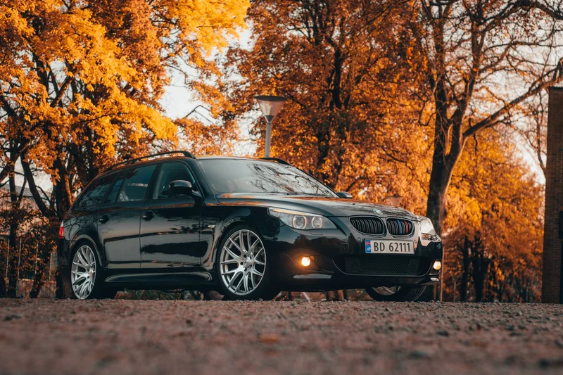 Svart BMW 5-serie Touring fotografert under høstfargede trær